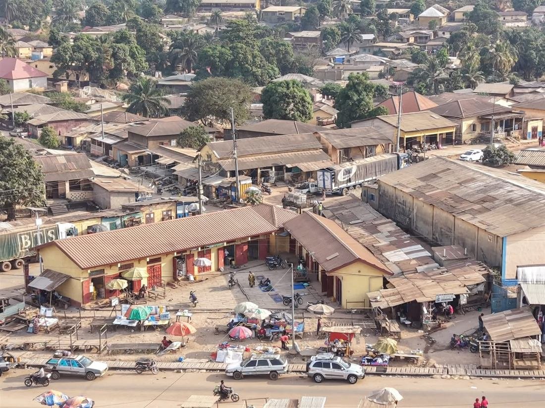 Vue aérienne du centre de Macenta : commerces, marché et habitations au pied des collines boisées